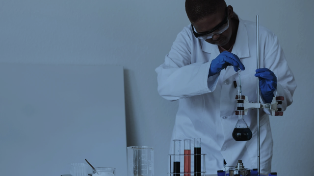 a scientist adding liquid to a beaker using a syringe