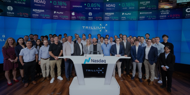 Trillium team standing behind Nasdaq podium.