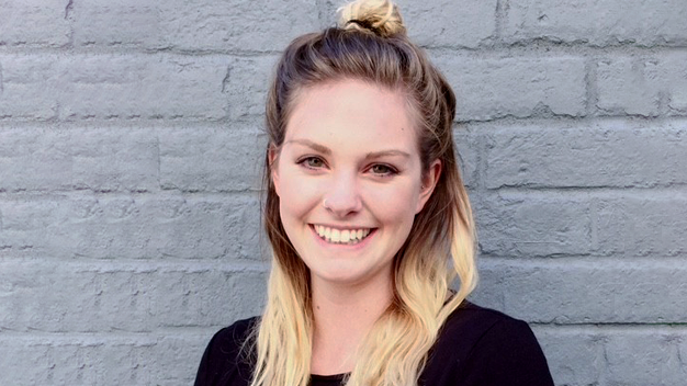 Jaime Shive portrait headshot in front of gray brick wall
