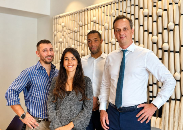 4 people in meeting room posing