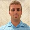 portrait of Mike Miller standing in front of wall with geometric arrow pattern