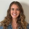 portrait of smiling Rachael Dempsey standing in front of off-white wall