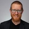portrait of Travis Gerke in front of gray background