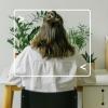 back view of woman sitting at a desk with plants on it and on the floor, woman is framed with computer terminal graphic